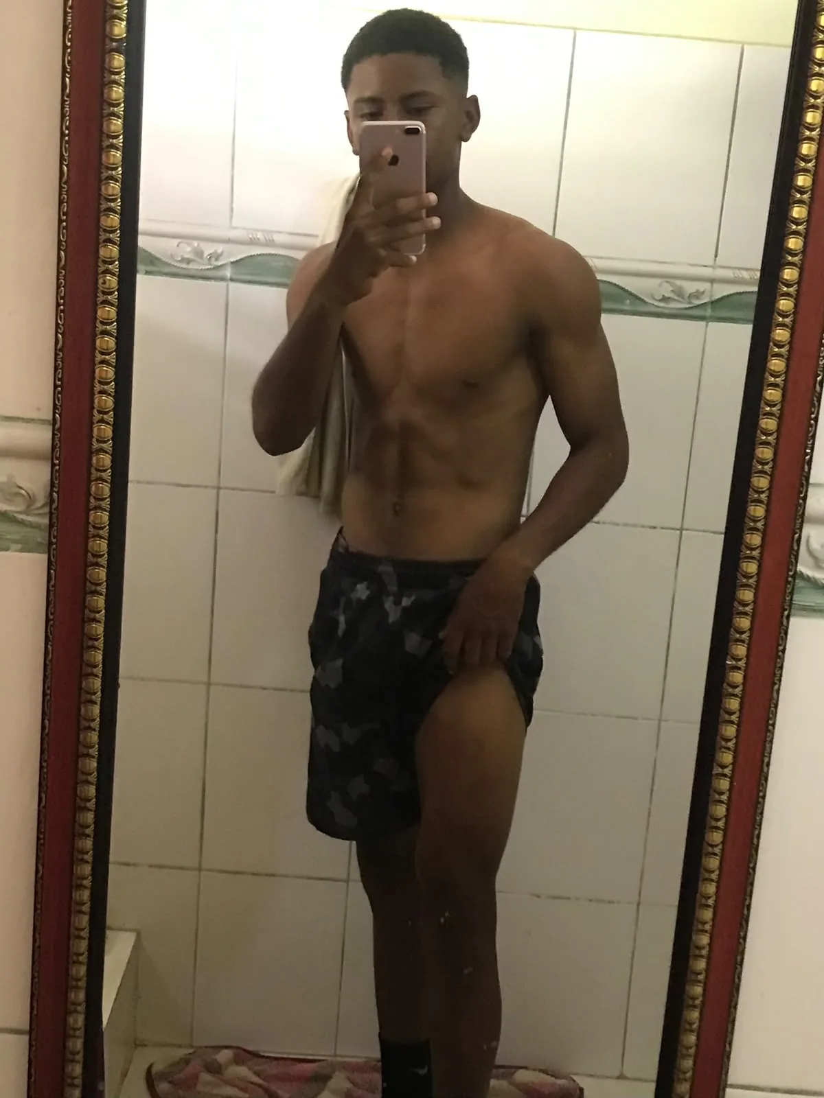 Antes del proceso: frente al espejo de un baño de azulejos blancos, con pantalón corto estampado