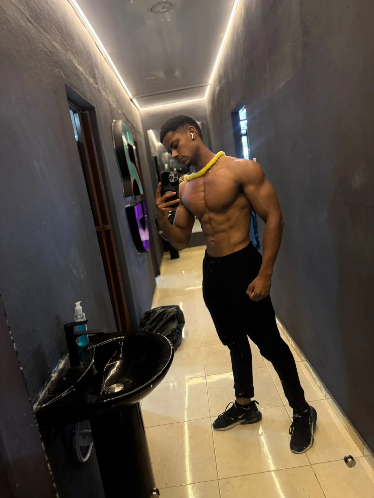 Después del proceso: frente al espejo en un pasillo, sin camiseta y con pantalón negro